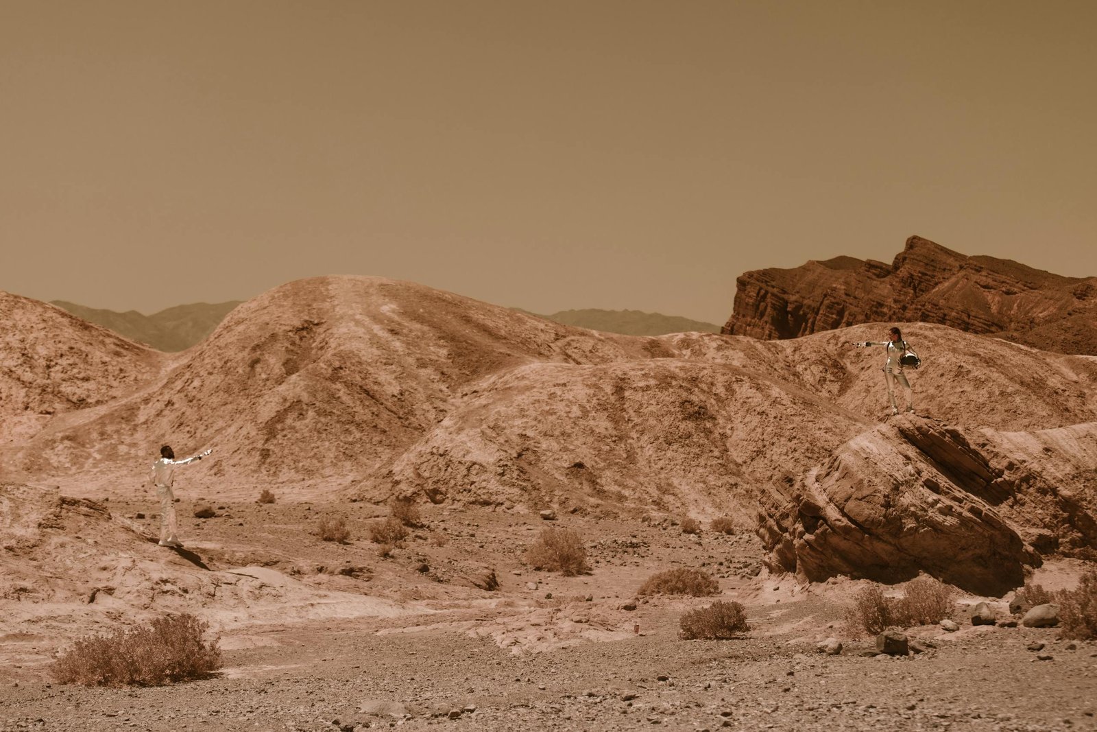 Two astronauts in a rocky desert landscape, evoking Mars exploration.